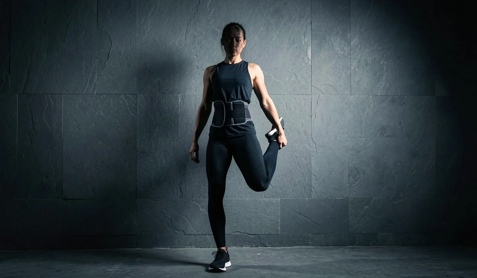 Person performing a standing forward fold stretch in a gym